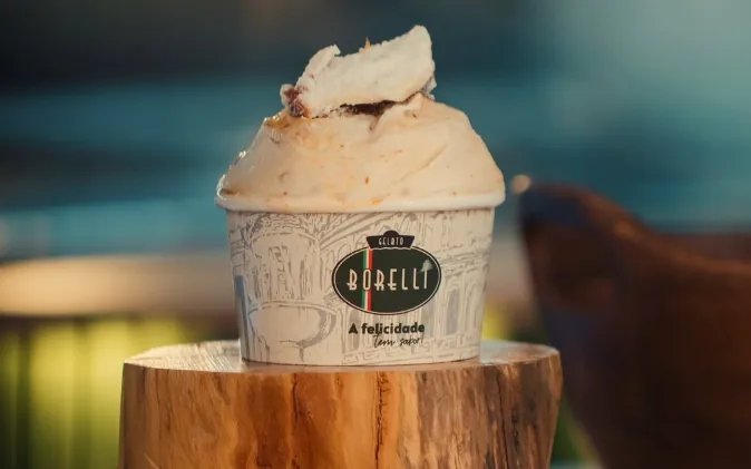 Copo de gelato Gelato Borelli servido sobre base de madeira, com nozes